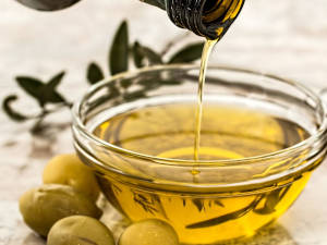 Eine Schale mit Olivenöl aus Italirn, daneben einige Oliven