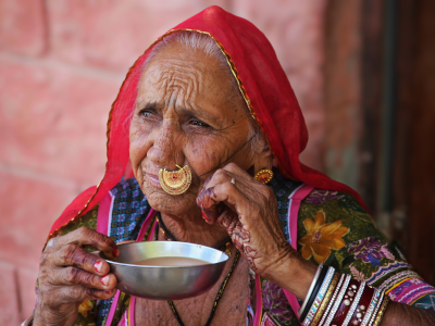 Bishnoi-Frau in Rajasthan, Indien. Sie trägt bunte, traditionelle Kleidung und auffällige Armreifen. An der Nase trägt sie ein großen, verzierten Schmuck.