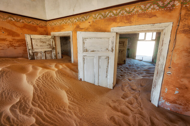 Innenraum eines verlassenen Hauses in Kolmanskop, Namibia, gefüllt mit Sanddünen. | Gebeco