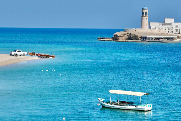 Hafen von Sur im Oman mit blauem Wasser, Strand und Leuchtturm im Hintergrund. | Gebeco