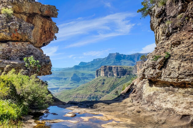 Blick durch Felsformationen auf das Bergpanorama der Drakensberge in Südafrika bei klarem Himmel. | Gebeco