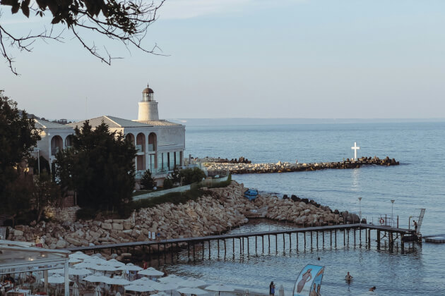 Leuchtturm mit weißem Gebäude an der Küste von Varna, mit Blick aufs Schwarze Meer und Strandpromenade. < Gebeco