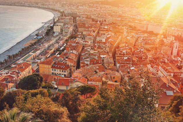 Panoramablick auf die Altstadt von Nizza bei Sonnenuntergang mit roten Dächern, der Promenade und dem Mittelmeer im Hintergrund. | Gebeco