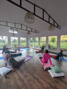 Frauen beim Yoga im Women Empowerment Center in Nordindien mit Blick auf grüne Hügellandschaft, Indien I Gebeco