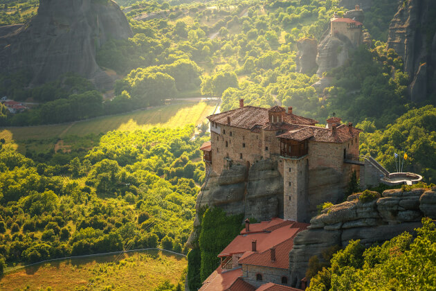 Meteora-Kloster in Griechenland auf steilem Felsen bei Sonnenlicht, umgeben von grüner Landschaft und Bergen. | Gebeco