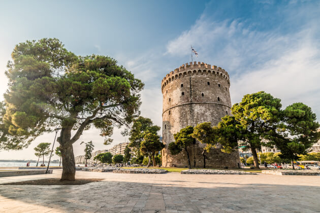 Weißer Turm von Thessaloniki an der Uferpromenade, umgeben von Bäumen bei sonnigem Wetter. | Gebeco