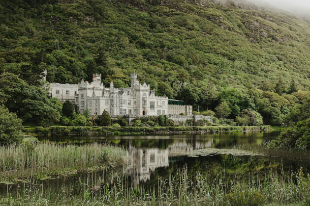 Kylemore Abbey in Connemara vor bewaldeter Bergkulisse mit Spiegelung im See. | Gebeco