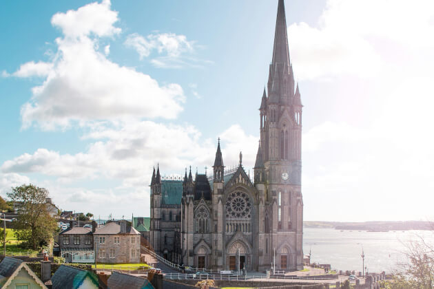 Neogotische St. Colman’s Cathedral in Cobh bei Cork mit markantem Glockenturm und Blick auf das Meer. | Gebeco