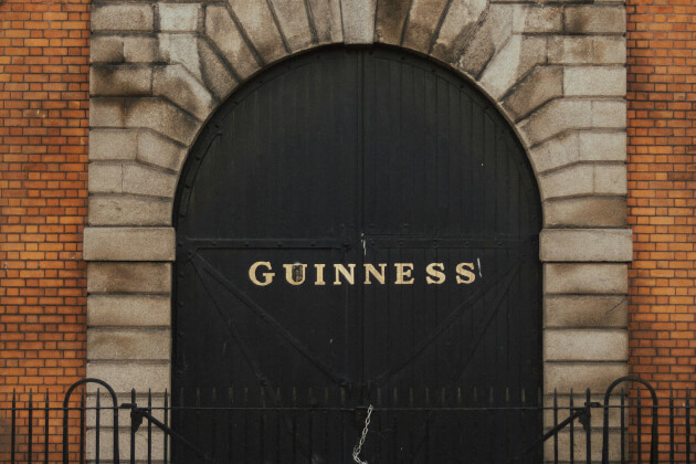 Schwarzes Tor der Guinness-Brauerei in Dublin mit markanter Schrift und Backsteinfassade. | Gebeco