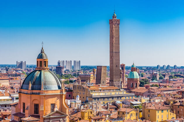 anoramablick auf Bologna mit den markanten Türmen Asinelli und Garisenda sowie historischen Kuppelbauten unter klarem Himmel. | Gebeco 