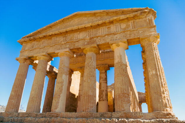 Griechischer Tempel im Tal der Tempel bei Agrigent auf Sizilien vor blauem Himmel. < Gebeco
