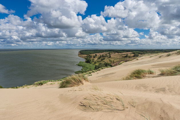 Sanddünen der Kurischen Nehrung bei Nida mit Blick auf das Haff und weite Landschaft unter dramatischem Wolkenhimmel. | Gebeco