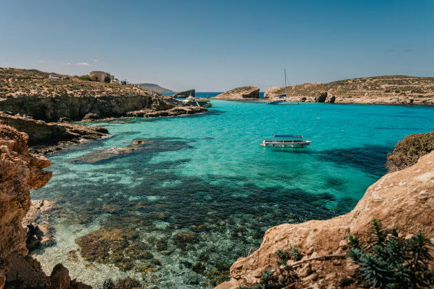 Türkisfarbenes Wasser der Blauen Lagune auf Comino mit Felsbuchten und Booten bei sonnigem Wetter. | Gebeco