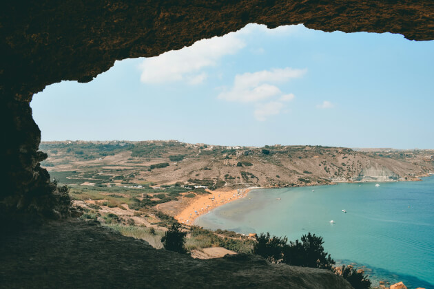 Panoramablick auf die goldene Bucht Ramla Bay auf Gozo, eingerahmt von einer Höhle im Vordergrund. | Gebeco