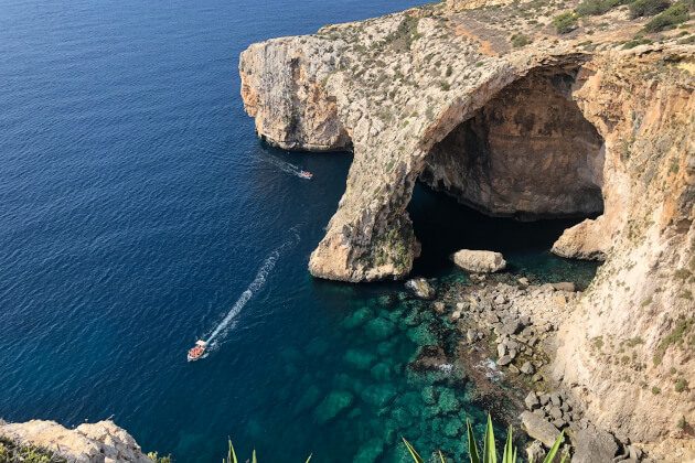 Steilküste und Felsbogen der Blauen Grotte auf Malta mit türkisblauem Wasser und Booten. | Gebeco