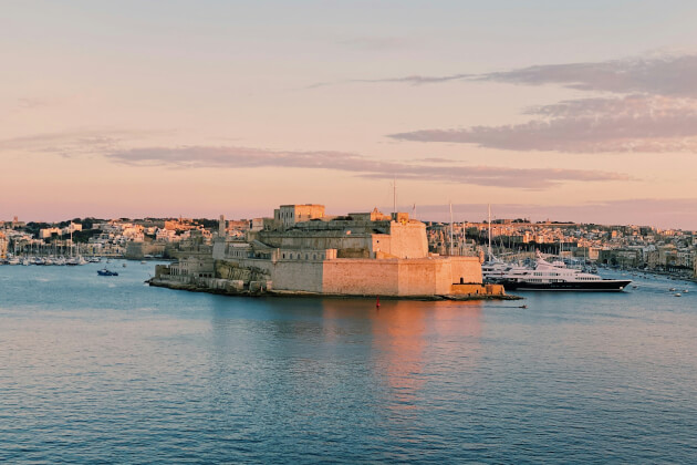 Barocke Kirche in Senglea mit maltesischer und vatikanischer Flagge vor strahlend blauem Himmel. | Gebeco