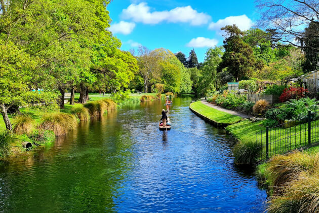 Idyllische Bootsfahrt auf dem Avon River im botanischen Garten von Christchurch, umgeben von üppigem Grün und blauem Himmel. | Gebeco