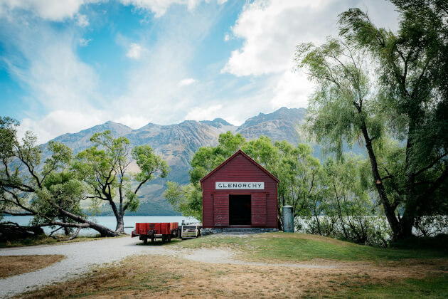 Historisches rotes Bootshaus in Glenorchy am Lake Wakatipu, umgeben von Bergen in Neuseeland. | Gebeco