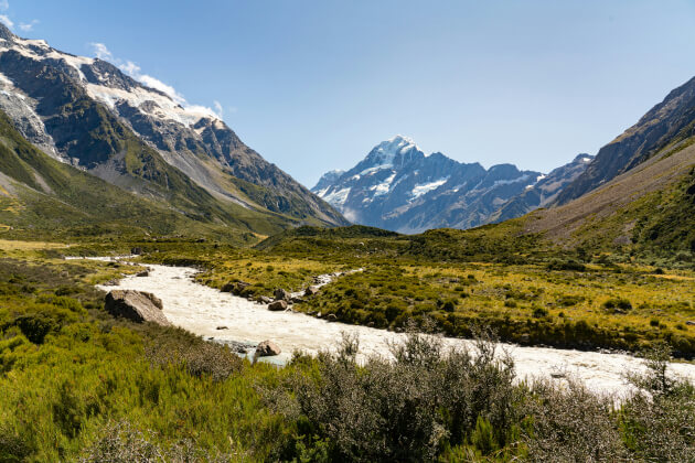 Alpenpanorama mit dem Mount Cook in Neuseeland, grünes Tal und schneebedeckte Gipfel entlang des Hooker Valley Tracks bei klarem Himmel. | Gebeco