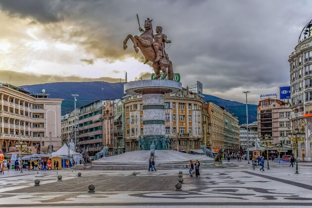 Reiterstatue auf dem zentralen Mazedonienplatz in Skopje vor historischer Gebäudezeile und dramatischem Himmelspanorama. | Gebeco