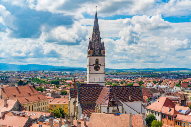 Evangelische Stadtpfarrkirche von Sibiu mit farbigem Ziegeldach über den Dächern der Altstadt in Siebenbürgen. | Gebeco