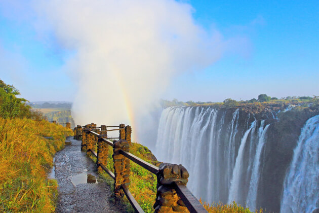 Aussichtspfad an den Victoriafällen in Simbabwe mit aufsteigendem Sprühnebel und Regenbogen. | Gebeco