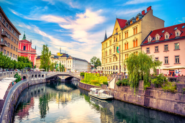 Blick auf die Drei Brücken und die Altstadt von Ljubljana mit Boot auf der Ljubljanica bei Sonnenuntergang. | Gebeco