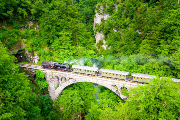Historische Dampflok auf dem Solkan-Viadukt bei Nova Gorica, eingebettet in dichte grüne Berglandschaft. | Gebeco