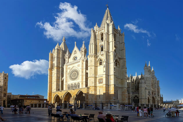 Gotische Kathedrale von León auf einem sonnigen Platz mit Menschen im Vordergrund. | Gebeoo
