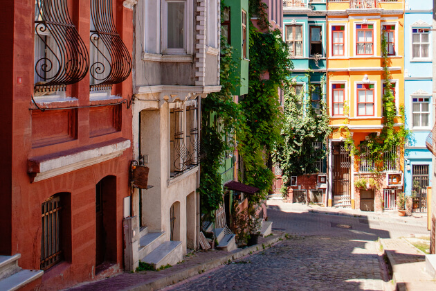 Bunte Häuserfassaden im historischen Balat-Viertel von Istanbul mit Kopfsteinpflaster und Pflanzenbewuchs. | Gebeco