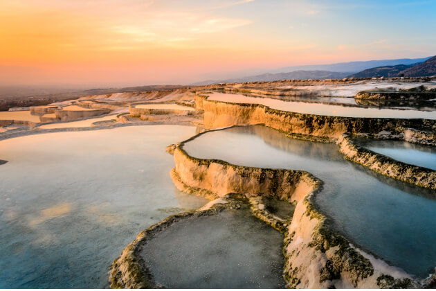 Naturwunder Pamukkale mit schneeweißen Kalksinterterrassen und Thermalwasser bei Sonnenuntergang. | Gebeco