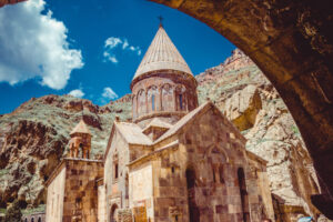 Geghard-Kloster in Armenien mit spitzem Kuppeldach, eingebettet in eine Felsenschlucht bei blauem Himmel. | Gebeco