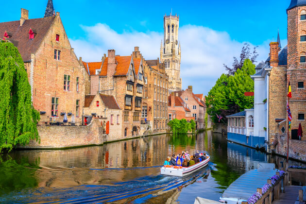 Bootsfahrt auf dem Kanal in der Altstadt von Brügge mit historischen Häusern und Belfried im Hintergrund. | Gebeco