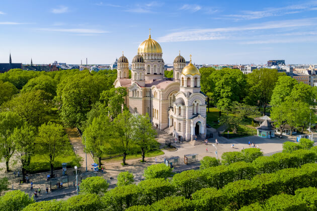 Goldene Kuppeln der Christi-Geburt-Kathedrale in Riga im Frühling, umgeben von grüner Parklandschaft in Lettland. | Gebeco