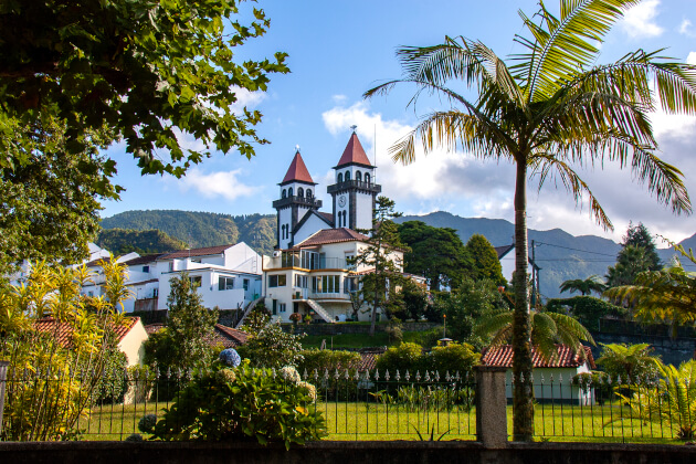 Historische Kirche mit zwei Türmen auf der Azoreninsel São Miguel, umgeben von tropischem Garten und Palmen. | Gebeco