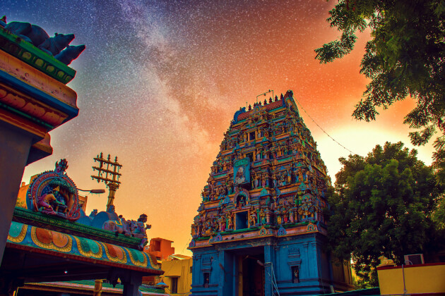 Farbenfroher Hindu-Tempel in Chennai bei Abenddämmerung mit leuchtenden Statuen und dem Sternenhimmel im Hintergrund. | Gebeco