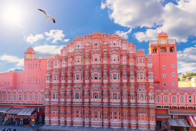 Das berühmte Hawa Mahal in Jaipur mit seiner rosafarbenen Fassade und unzähligen Fenstern unter blauem Himmel. | Gebeco