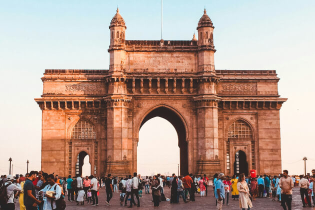 Das monumentale Gateway of India in Mumbai bei Sonnenuntergang, mit vielen Besuchern auf dem Vorplatz. | Gebeco