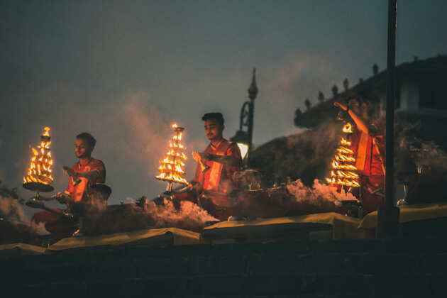 Priester führen die traditionelle Ganga-Aarti-Zeremonie bei Sonnenuntergang in Varanasi am Ganges durch. | Gebeco