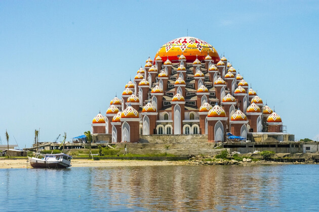 Die farbenfrohe 99-Kuppel-Moschee am Ufer von Makassar, Indonesien, spiegelt sich im ruhigen Wasser. | Gebeco