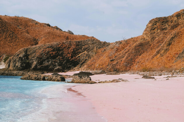 Rosa Sandstrand am Pink Beach auf der Insel Komodo in Indonesien mit türkisblauem Meer und Felsformationen. | Gebeco