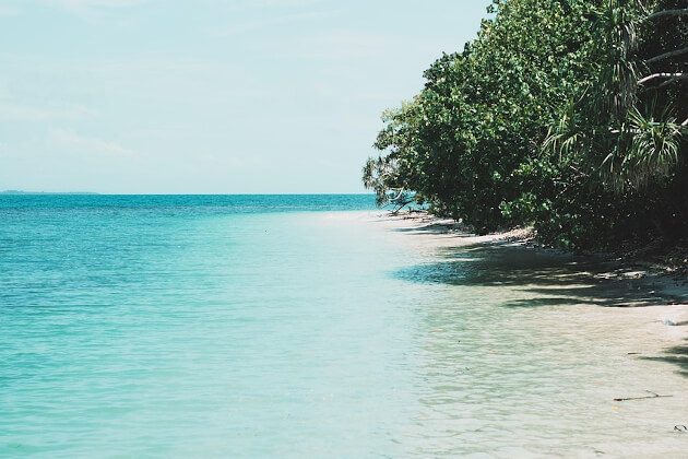 Weißer Sandstrand mit türkisfarbenem Wasser und dichter grüner Vegetation auf den Gili-Inseln bei Lombok, Indonesien. | Gebeco