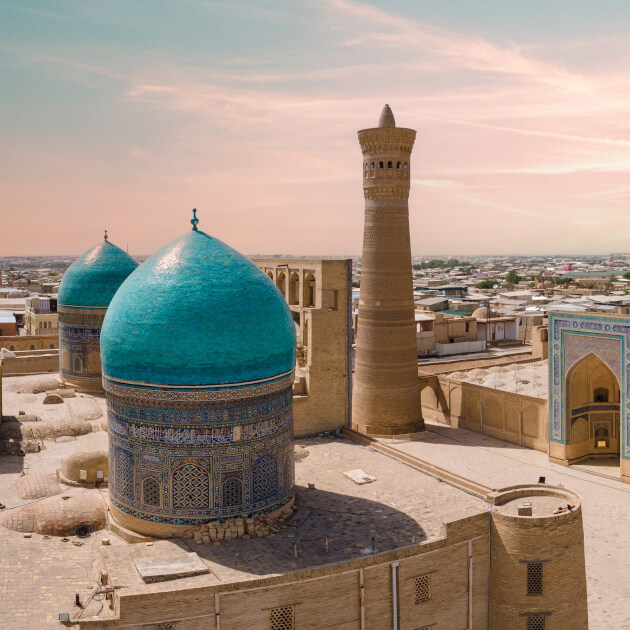Panorama mit den türkisfarbenen Kuppeln des Chor Minor Ensembles und Minarett bei Sonnenuntergang in Buchara. | Gebeco