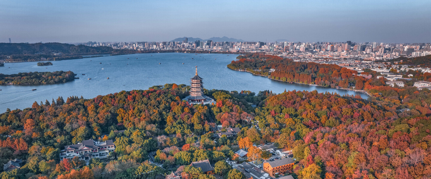 Luftaufnahme des Westsees in Hangzhou mit Leifeng-Pagode, herbstlich gefärbten Bäumen und der Stadt im Hintergrund