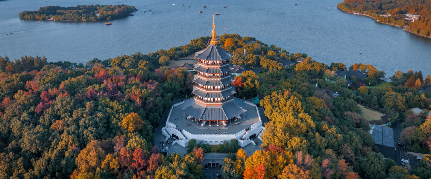 Luftaufnahme der Leifeng-Pagode am Westsee in Hangzhou, umgeben von herbstlich gefärbten Bäumen und dem See im Hintergrund