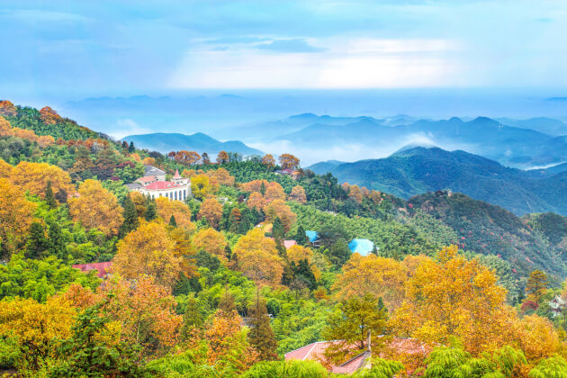 Herbstlandschaft mit Villen in Moganshan, China – Blick auf bewaldete Hügel unter Nebelschleier