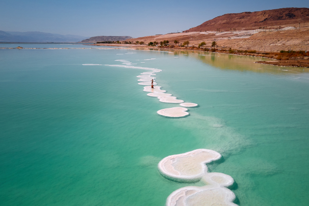 Totes Meer Israel mit Salzformationen im türkisblauen Wasser und Frau auf Salzpfad