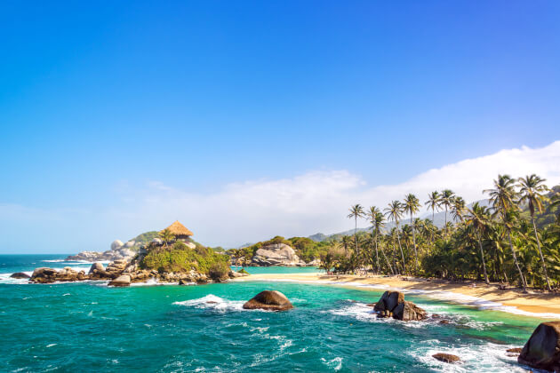 Karibikstrand mit Palmen, türkisfarbenem Meer und Felsen im Tayrona-Nationalpark an Kolumbiens Küste. | Gebeco