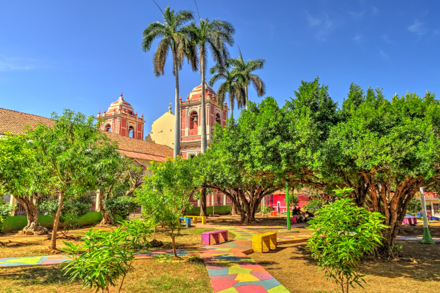 Begrünter Innenhof mit buntem Weg in León in Nicaragua vor historischen Gebäuden aus der Kolonialzeit.