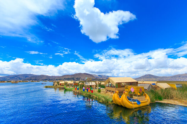 Totora-Boote, bunte Kleidung und traditionelle Schilfhütten auf schwimmender Uros-Insel im Titicacasee, Peru. | Gebeco